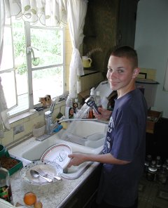 Matthew washing the dishes with a smile.